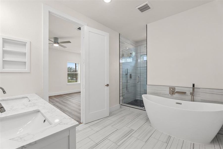 Bathroom with a freestanding tub, double vanity, a shower stall, a ceiling fan, and recessed lighting Bathroom with a freestanding tub, double vanity, a shower stall, a ceiling fan, and recessed lighting
