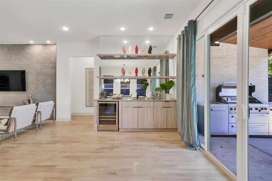 Bar with sink, light hardwood / wood-style flooring, light brown cabinets, and wine cooler