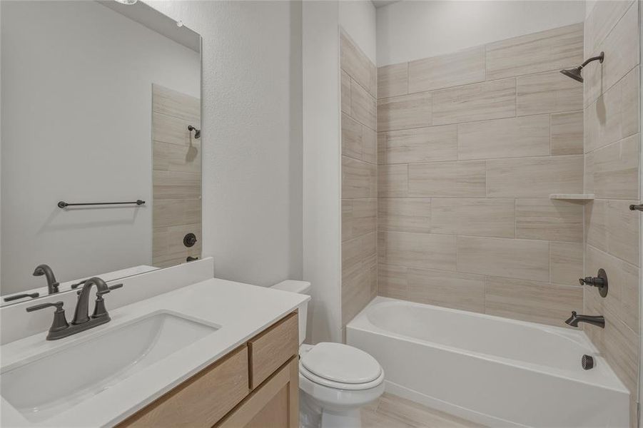 Bathroom featuring a vanity with light wood-finish cabinetry, a white countertop, and an undermount sink with dark bronze fixtures Bathroom featuring a vanity with light wood-finish cabinetry, a white countertop, and an undermount sink with dark bronze fixtures