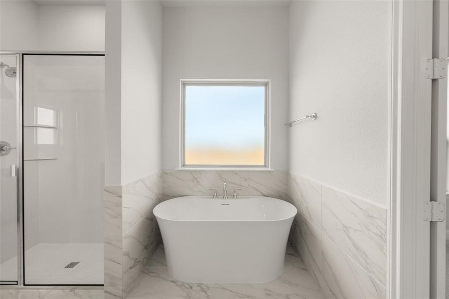 Bathroom featuring marble finish flooring, a shower stall, a freestanding tub, a wainscoted wall, and tile walls Bathroom featuring marble finish flooring, a shower stall, a freestanding tub, a wainscoted wall, and tile walls