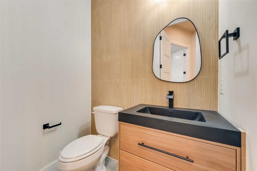 Half bath with toilet, vanity, decorative backsplash, and tile walls Half bath with toilet, vanity, decorative backsplash, and tile walls