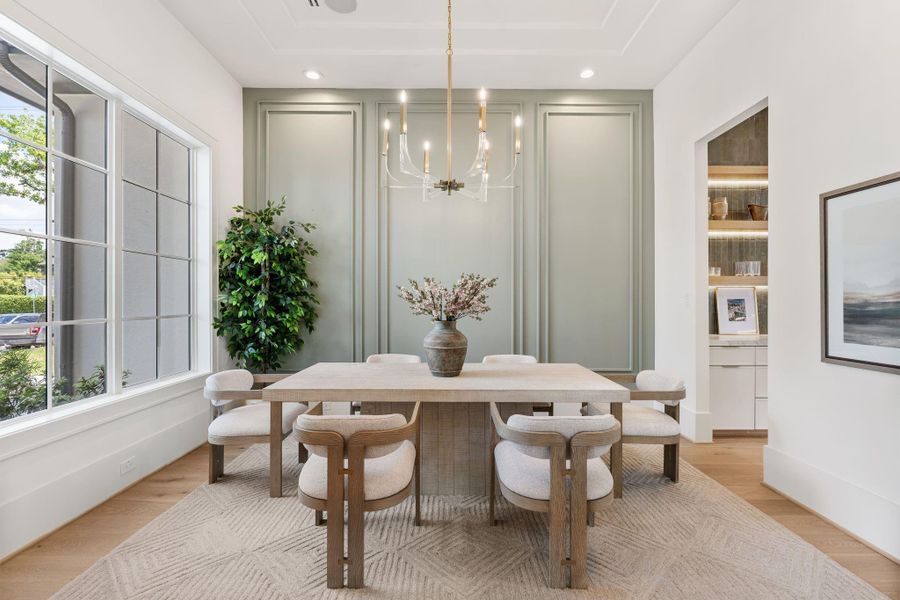 The dining room is anchored by expansive windows that fill the space with natural light, enhancing the scale and architectural detailing while maintaining a bright, airy feel.