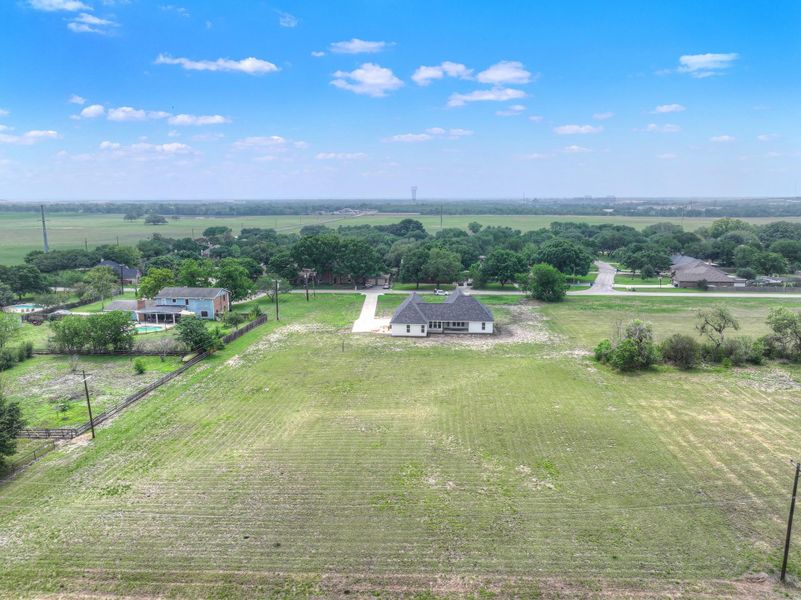 Expansive land parcel featuring a contemporary single-story residence with a light-colored exterior and a dark-shingled roof