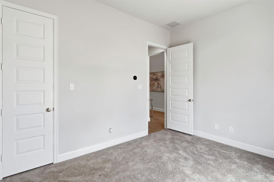 Another view highlights the room's flexible layout, spacious proportions, and convenient access to the nearby hall bath. A large closet provides ample storage while maintaining a clean, uncluttered feel.