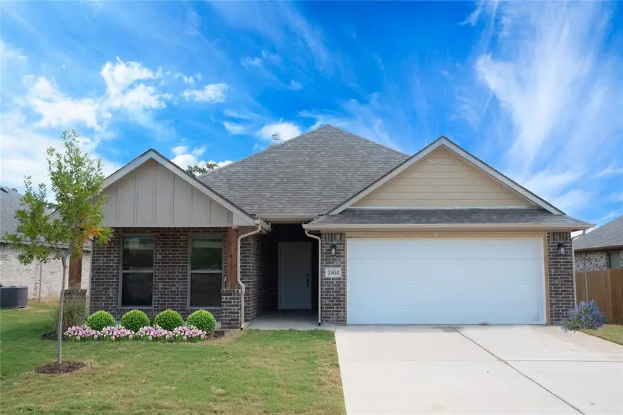 View of front of home with a front lawn, driveway, an attached garage, and brick siding