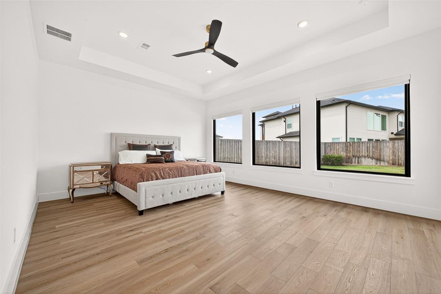 PRIMARY 1 DOWNSTAIRS: The downstairs primary retreat is tucked privately at the rear of the home and showcases beautiful tray ceilings, recessed lighting, and oversized windows overlooking the pool and backyard oasis.