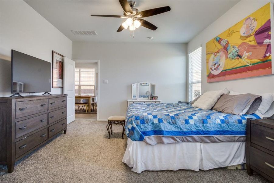 Bedroom featuring a ceiling fan, visible vents, and light carpet