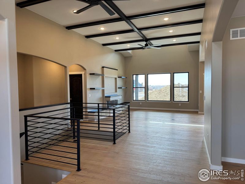 Open floor plan with expansive windows, high ceilings, wrought iron railing.