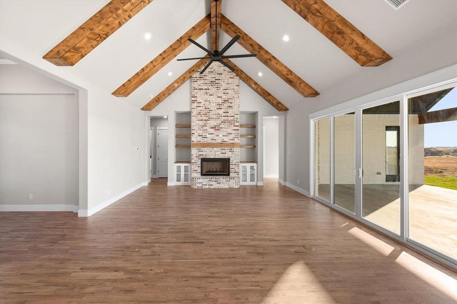 Unfurnished living room with beamed ceiling, dark wood-type flooring, a fireplace, high vaulted ceiling, and ceiling fan