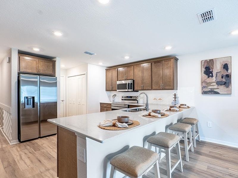 Your beautiful kitchen includes quartz and high-end finishes, along with ample cabinet space and a pantry - Azalea townhome by Highland Homes