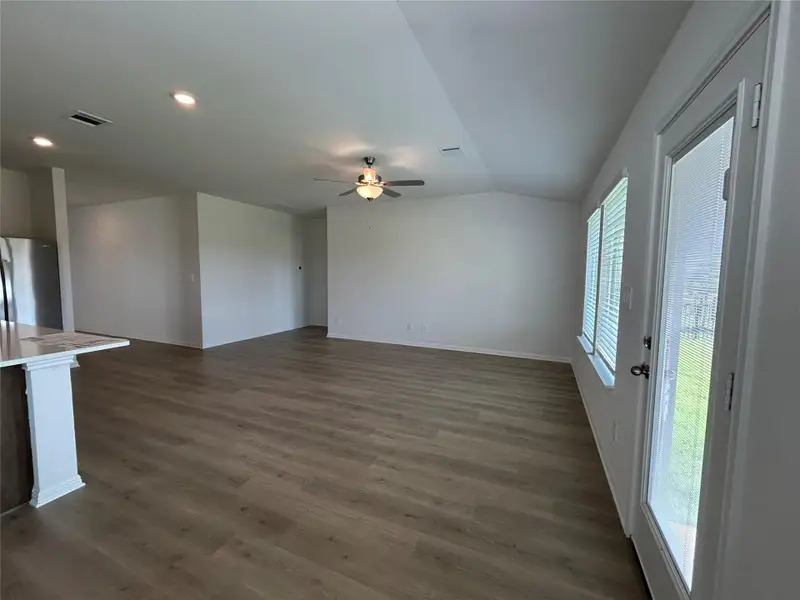 Unfurnished living room with dark wood-type flooring, vaulted ceiling, ceiling fan, and recessed lighting Unfurnished living room with dark wood-type flooring, vaulted ceiling, ceiling fan, and recessed lighting