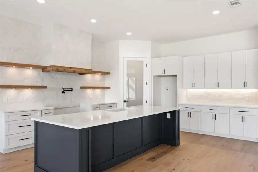 Culinary delights await in this bright kitchen with a spacious island, rich hardwood floors, and ample white cabinetry. Culinary delights await in this bright kitchen with a spacious island, rich hardwood floors, and ample white cabinetry.