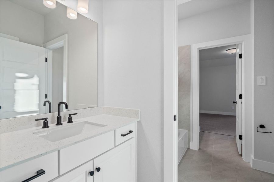 Convenient Jack and Jill bathroom provides private en suite access from two secondary bedrooms, featuring a modern dual vanity with crisp white cabinetry, sleek quartz countertops, and matte black fixtures.