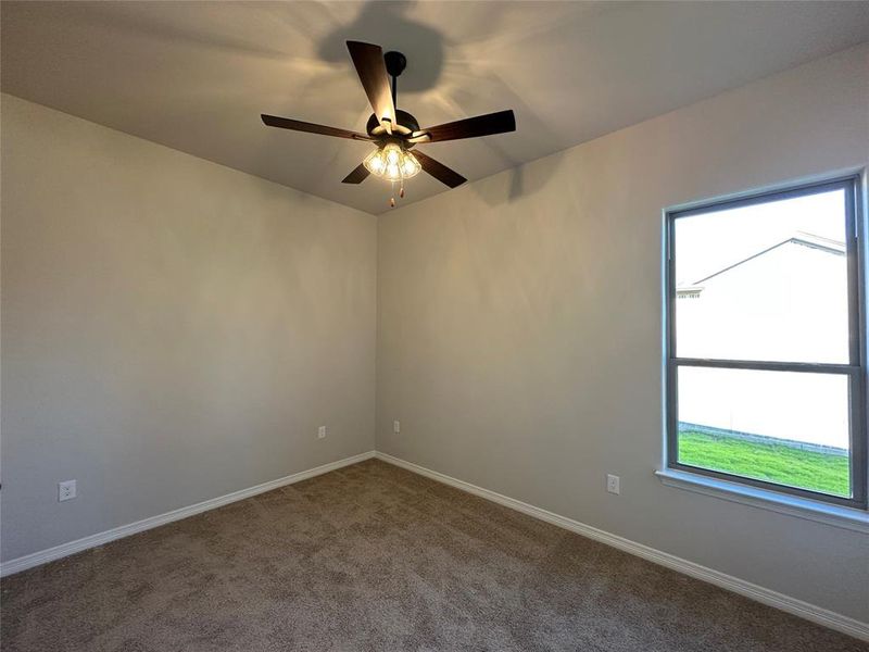 Carpeted spare room featuring baseboards and a ceiling fan Carpeted spare room featuring baseboards and a ceiling fan