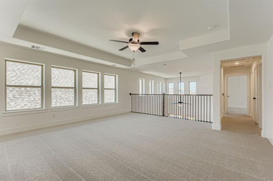 Unfurnished room featuring a tray ceiling, light colored carpet, a ceiling fan, and a smoke detector Unfurnished room featuring a tray ceiling, light colored carpet, a ceiling fan, and a smoke detector