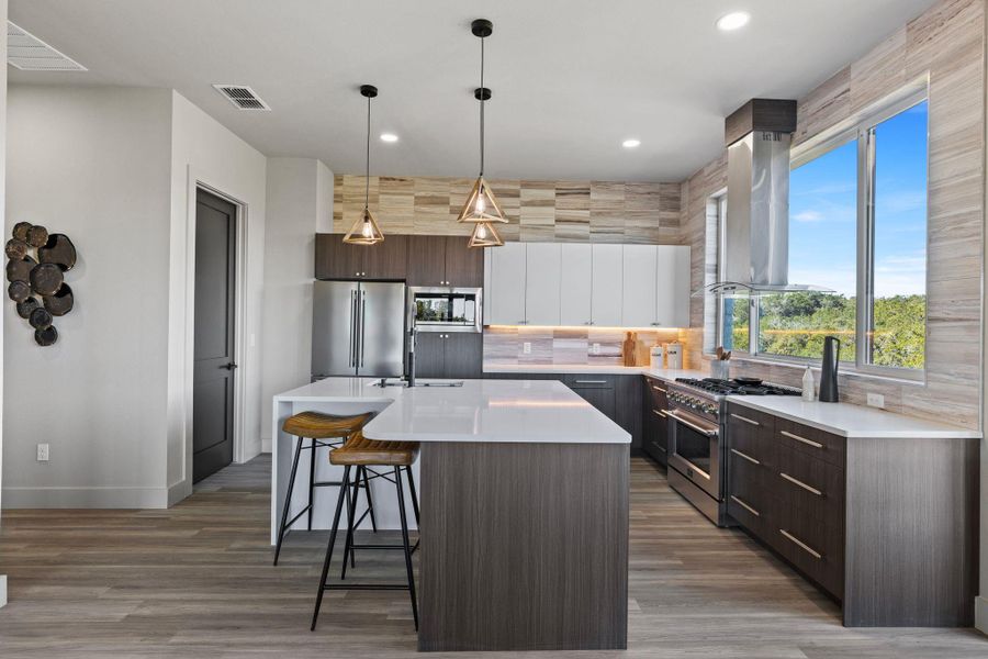 Kitchen with visible vents, a breakfast bar area, island range hood, decorative backsplash, and high end appliances