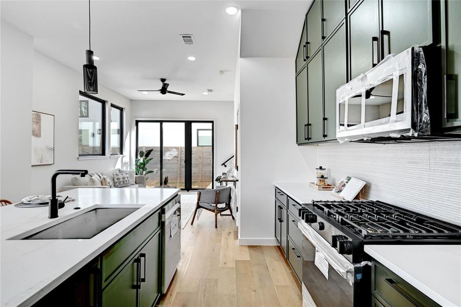 Kitchen featuring green cabinetry, range with gas cooktop, light wood-style floors, recessed lighting, and decorative light fixtures