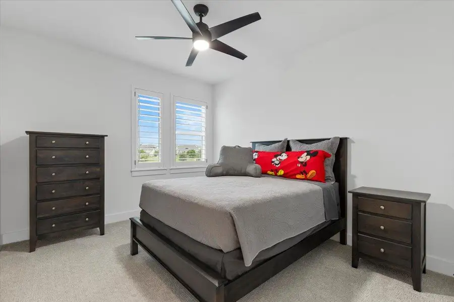 Bedroom with light colored carpet and a ceiling fan