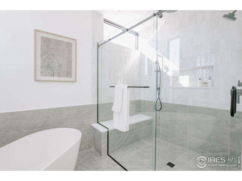 Ample shower with 3 shower heads, separate soaking tub and heated tile floors with wainscot detail for tub and shower area.