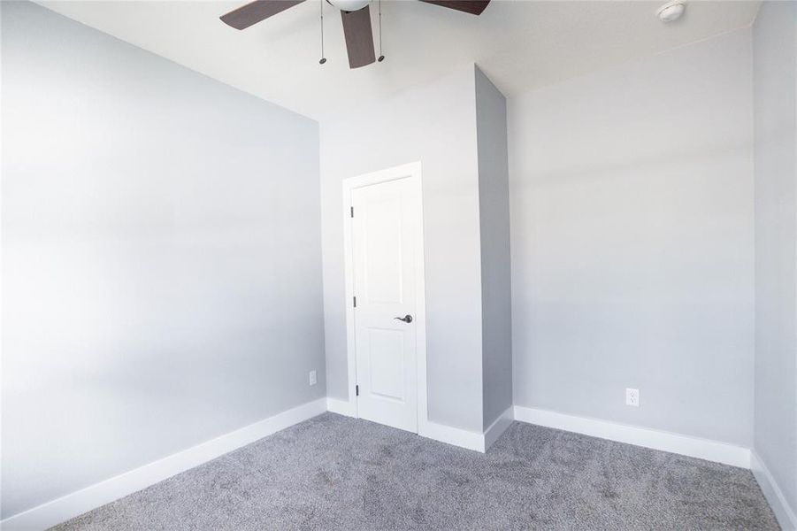 Carpeted spare room featuring baseboards and ceiling fan