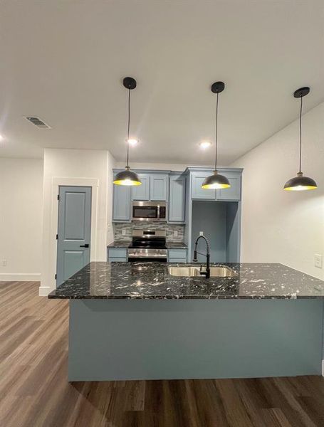 Kitchen with tasteful backsplash, appliances with stainless steel finishes, wood-type flooring, sink, and gray cabinetry