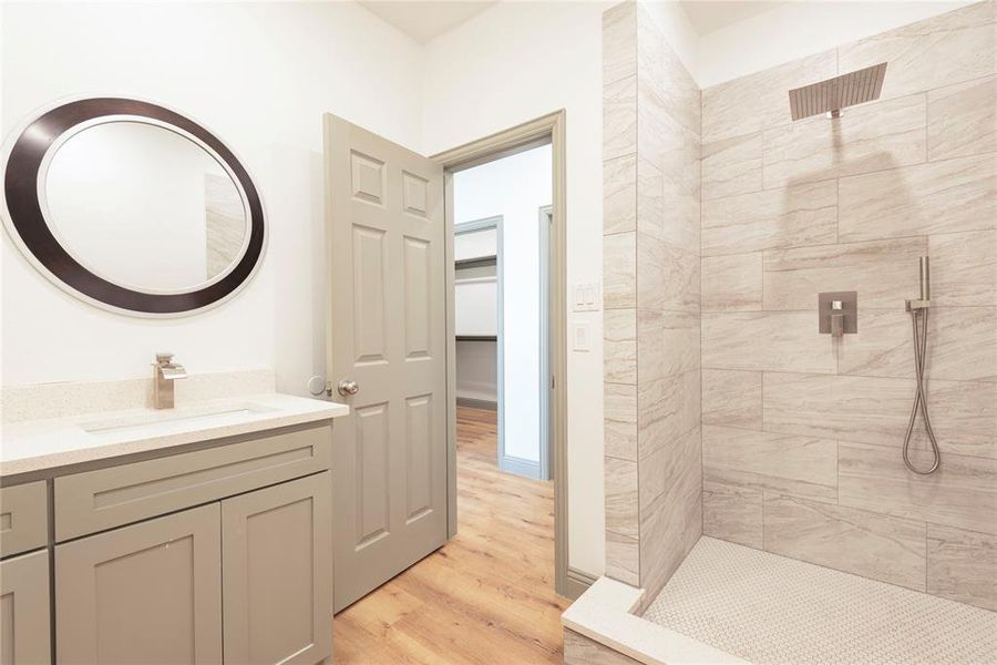 Bathroom with vanity, tiled shower, and light wood-style flooring