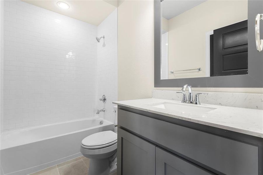 Full bathroom featuring vanity, tile patterned flooring, tiled shower / bath combo, and toilet