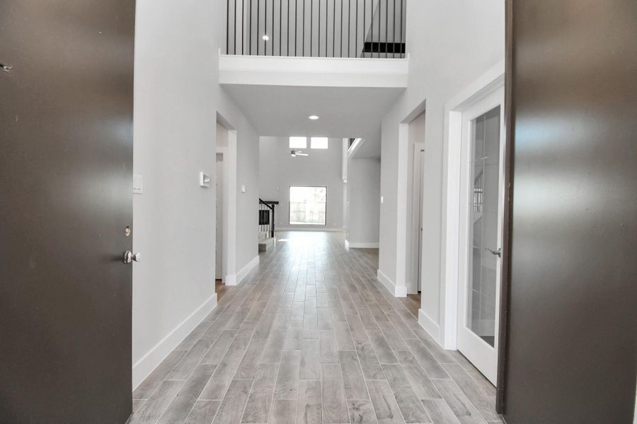 As you step into the threshold of this luxurious home, you'll soon be welcomed by an elegant glass door (to be installed). Inside, soaring ceilings amplify the spaciousness, while the refined wood-look tile flooring and oversized baseboards exude sophistication and charm. Sample photo of completed home with similar floor plan. Actual colors and selections may vary.
