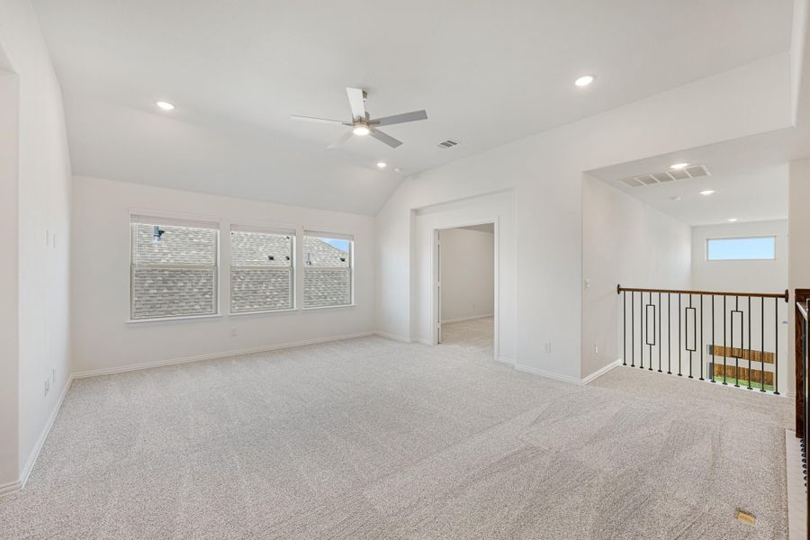 Spacious upstairs bonus room with vaulted ceiling, ceiling fan, carpet flooring, and staircase railing Spacious upstairs bonus room with vaulted ceiling, ceiling fan, carpet flooring, and staircase railing