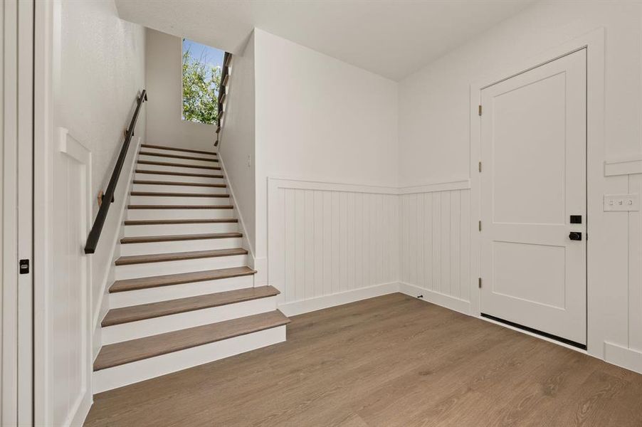 Entryway featuring wood finished floors, a wainscoted wall, and stairway Entryway featuring wood finished floors, a wainscoted wall, and stairway