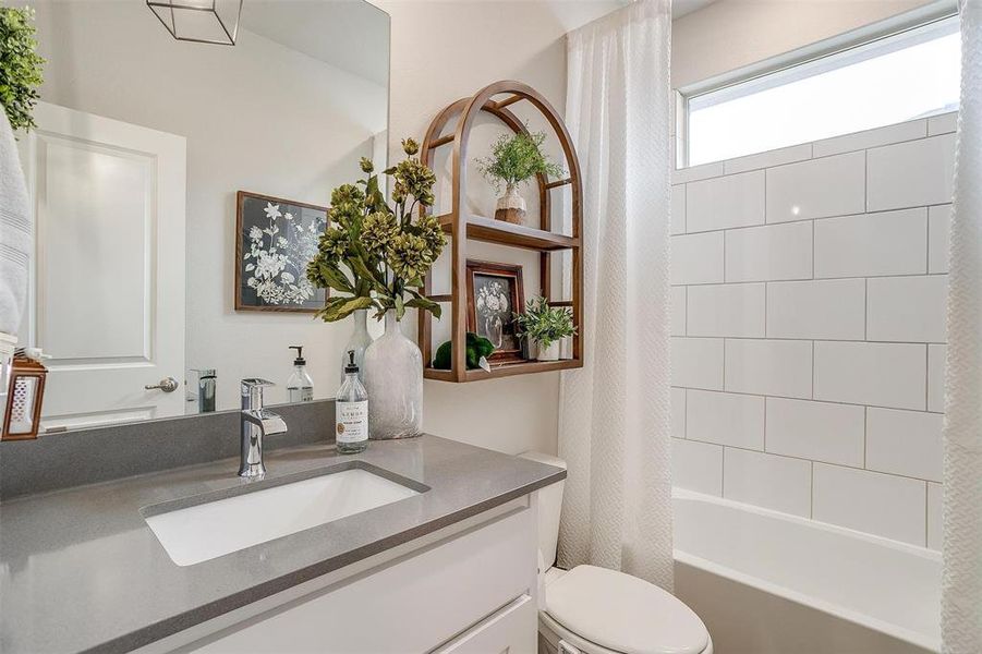 Bathroom featuring shower / bath combo, vanity, and toilet