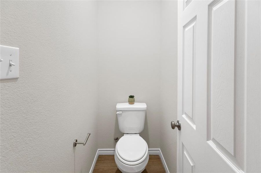Bathroom featuring dark wood-style floors and a textured wall Bathroom featuring dark wood-style floors and a textured wall