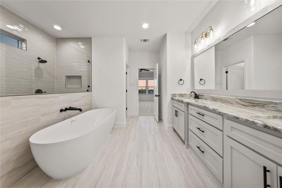 Full bathroom with a walk in shower, a soaking tub, double vanity, recessed lighting, and tile walls