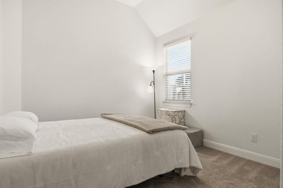 Carpeted bedroom with lofted ceiling and baseboards