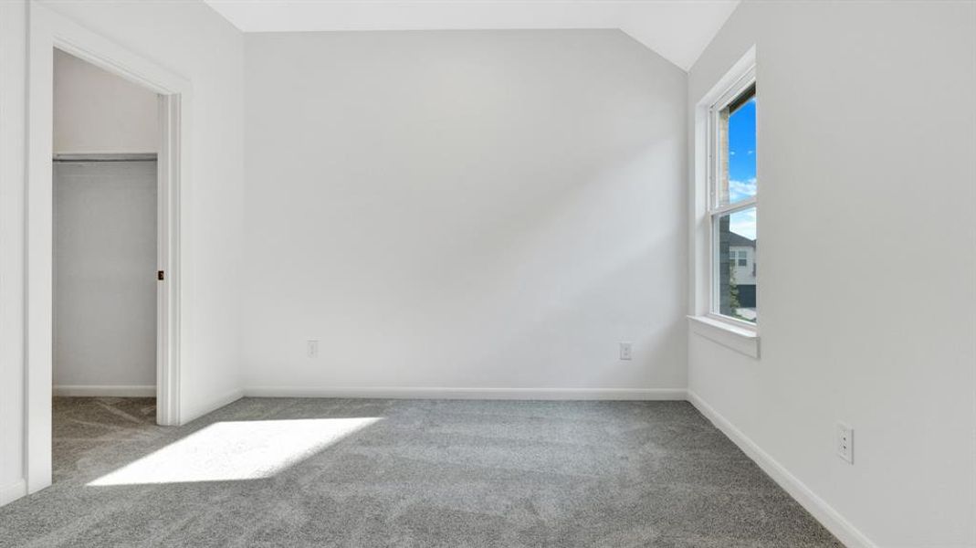 Unfurnished bedroom featuring lofted ceiling, a closet, and carpet floors