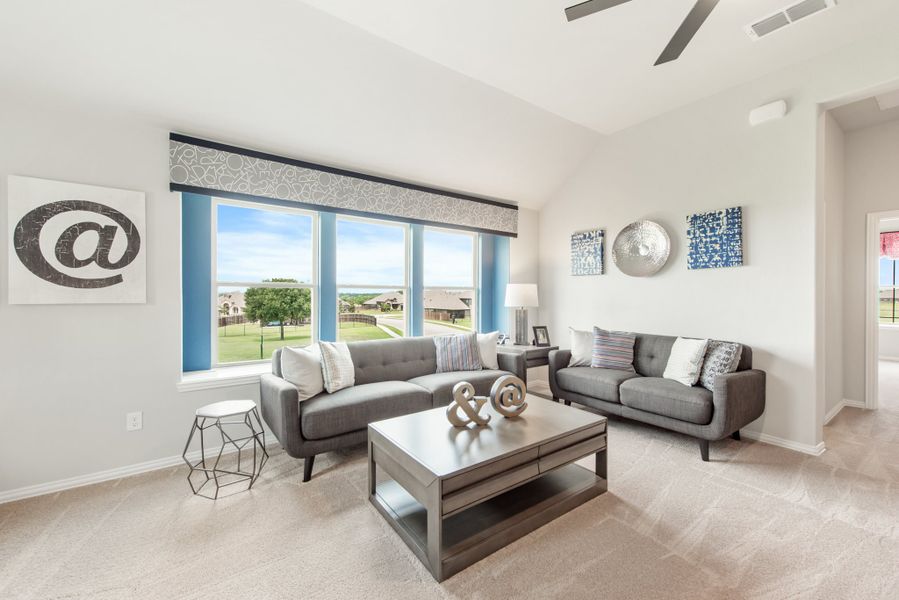 Living room with two gray sofas, wood coffee table, ceiling fan, and large windows with outdoor views