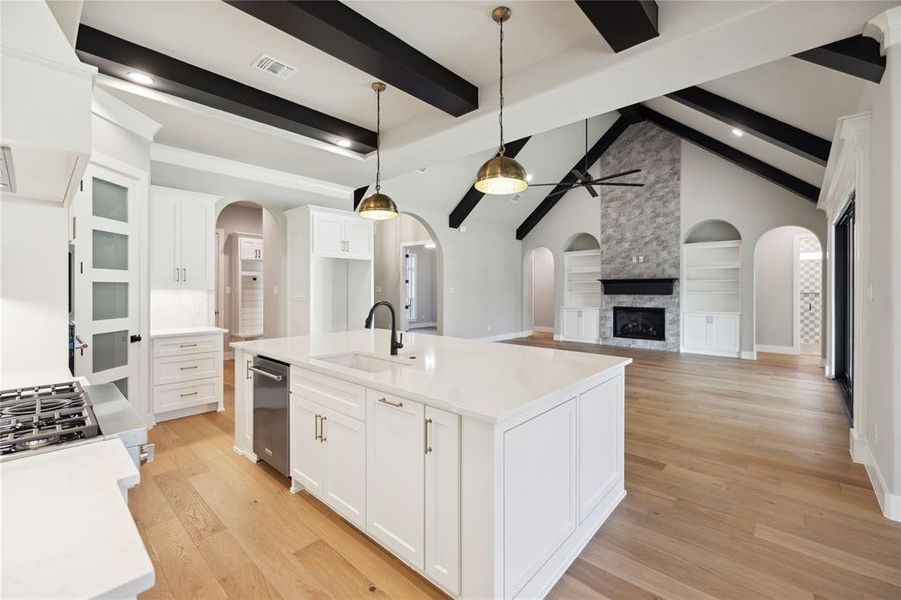 Kitchen with light hardwood / wood-style flooring, white cabinetry, sink, and an island with sink