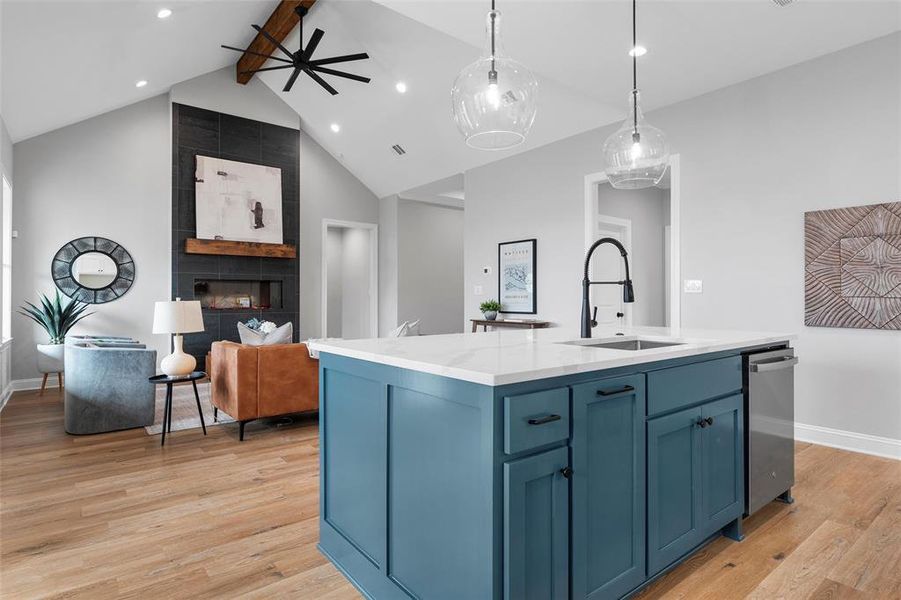 Kitchen featuring blue cabinets, light stone countertops, light wood-type flooring, decorative light fixtures, and beamed ceiling Kitchen featuring blue cabinets, light stone countertops, light wood-type flooring, decorative light fixtures, and beamed ceiling
