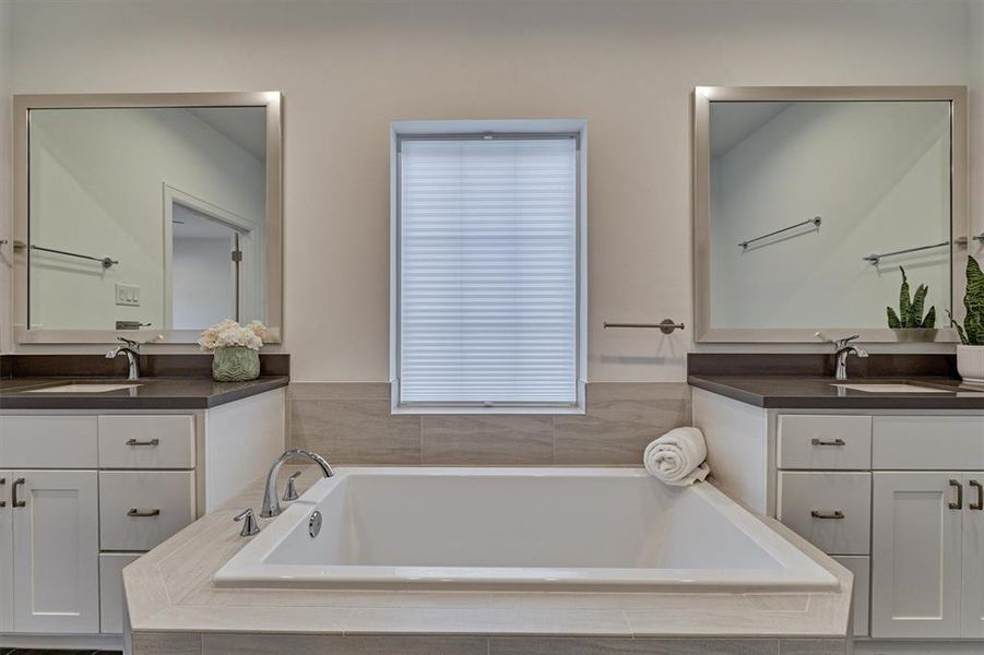 Oversized soaking tub is flanked by dual sinks and vanity space!