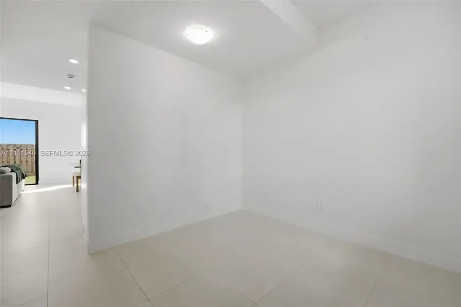 Neutral-toned large-format tile flooring and minimalist white walls with flush-mount ceiling lighting