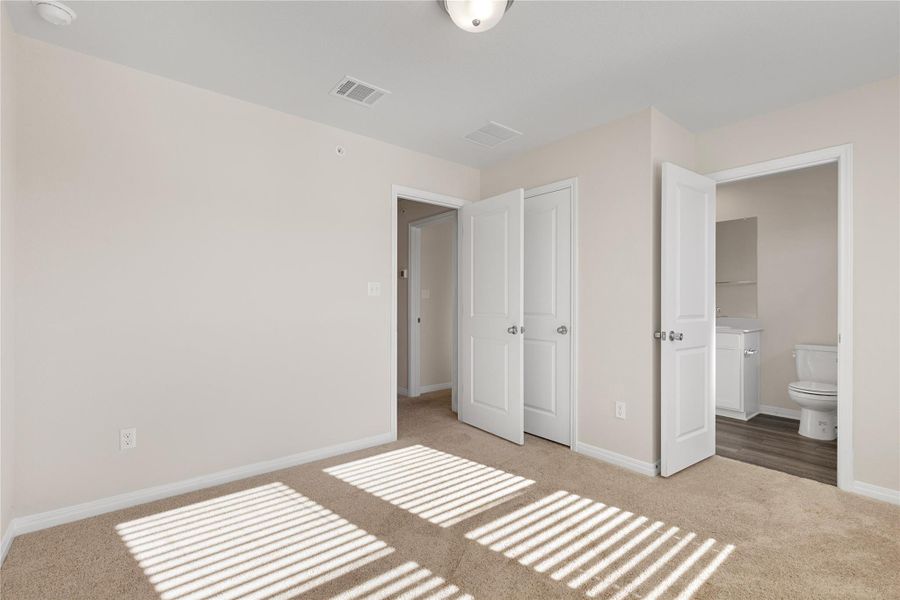Unfurnished bedroom featuring ensuite bathroom and light colored carpet Unfurnished bedroom featuring ensuite bathroom and light colored carpet