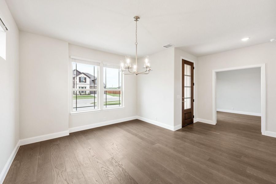 Empty dining room with hardwood floors, chandelier, and large windows overlooking neighborhood