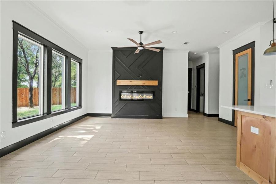 Unfurnished living room featuring crown molding, a fireplace, light wood-style floors, a ceiling fan, and recessed lighting