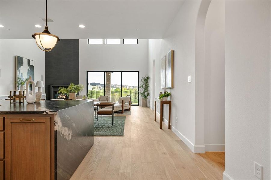 Corridor featuring light wood-type flooring, arched walkways, a towering ceiling, and recessed lighting Corridor featuring light wood-type flooring, arched walkways, a towering ceiling, and recessed lighting