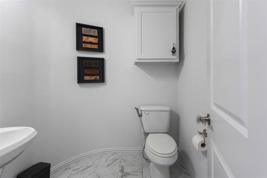 Half bath with light marble finish floors and baseboards