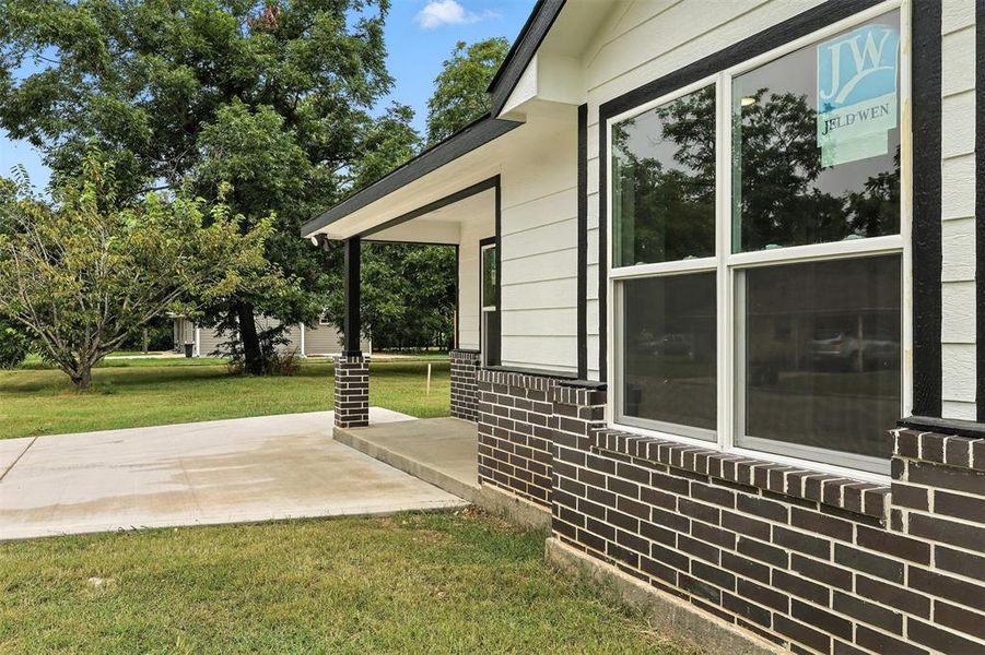 View of side of property with a patio area, a lawn, and brick siding View of side of property with a patio area, a lawn, and brick siding