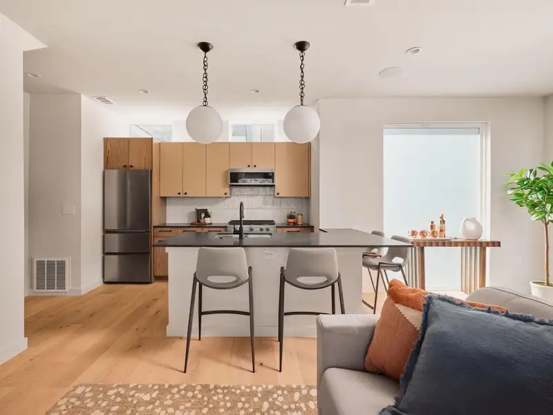 Kitchen featuring open floor plan, decorative light fixtures, freestanding refrigerator, and dark countertops