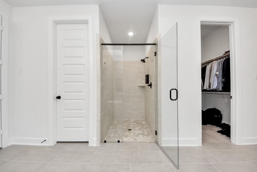 Elegant walk-in shower with upgraded tile and adjoining walk-in closet.