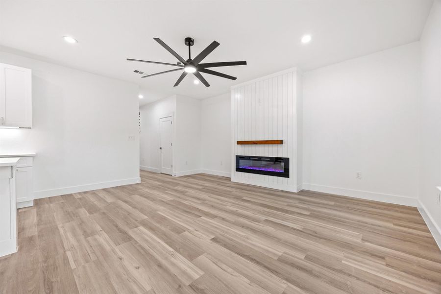 Unfurnished living room with a ceiling fan, light wood finished floors, a fireplace, and recessed lighting