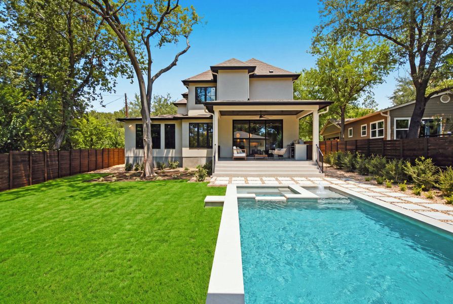 A sparkling swimming pool anchors the lushly landscaped backyard of this multi-story residence.